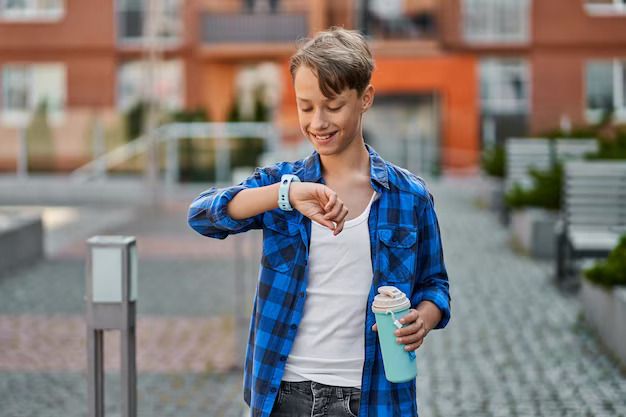 A little boy wearing blue smartwatch near school
